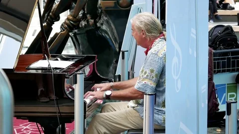 Motion of people playing piano at resting area inside airport terminal Stock Footage 78559210