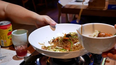 Motion of people sharing Korean stir-fried noodles to another on table Stock Footage 82045957