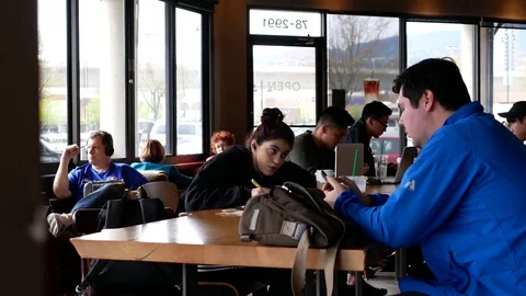 Motion of people using phone to check mail and doing homework inside Starbucks Video stock 83767466
