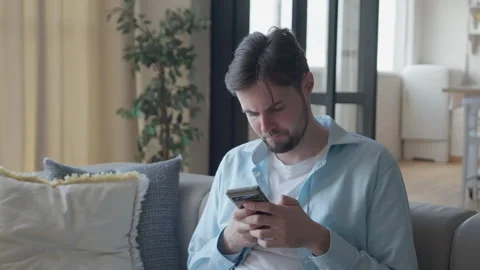Motion Portrait, Young Man on Sofa Receives Unexpected Smartphone News Stock Footage 301243640