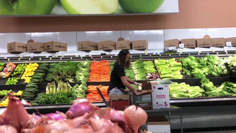 Motion of produce clerk stocking vegetable for sale inside Save on Foods store Stock Footage 93531211