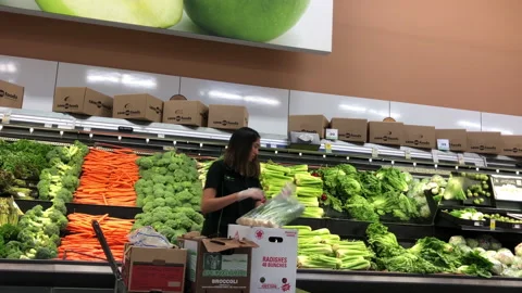 Motion of produce clerk stocking vegetable for sale inside Save on Foods store Video stock 93533910