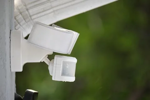 Motion sensor with light detector mounted on exterior wall of private house as Stock Photos