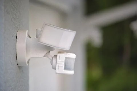 Motion sensor with light detector mounted on exterior wall of private house as Stock Photos