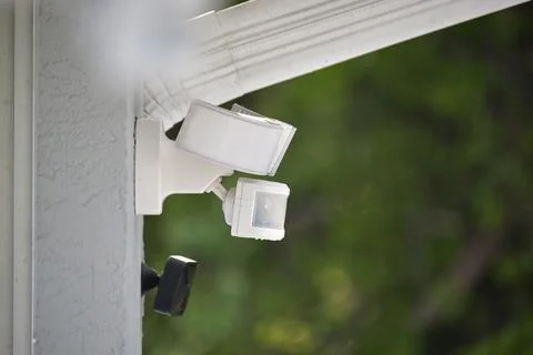 Motion sensor with light detector mounted on exterior wall of private house as Stock Photos