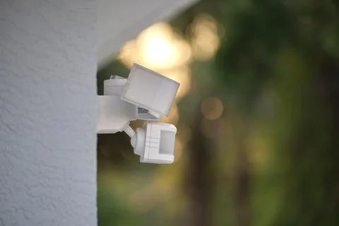 Motion sensor with light detector mounted on exterior wall of private house as Stock Photos