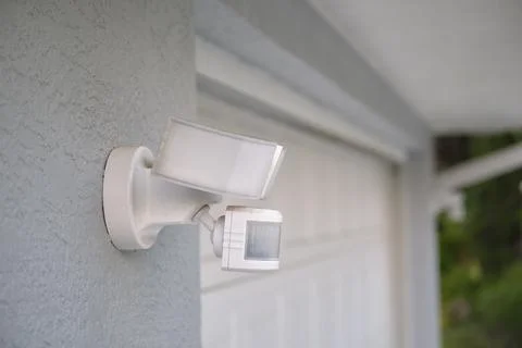 Motion sensor with light detector mounted on exterior wall of private house as Stock Photos