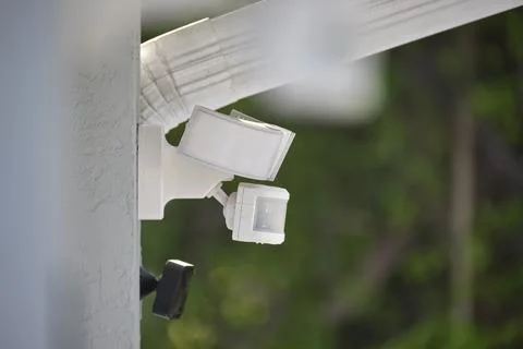 Motion sensor with light detector mounted on exterior wall of private house a Stock Photos