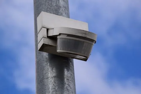 Motion Sensor Security Camera Mounted on Metal Pole Against Blue Sky Stock Photos