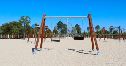 Motion shot approaching double empty swings swinging in playground Stock Footage 116011793