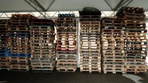 Motion to stacks of wooden pallets in light warehouse Video stock 147256977