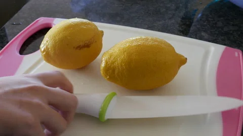 Motion of woman using ceramic chef knife and cutting lemon on cutting board Video stock 96576790