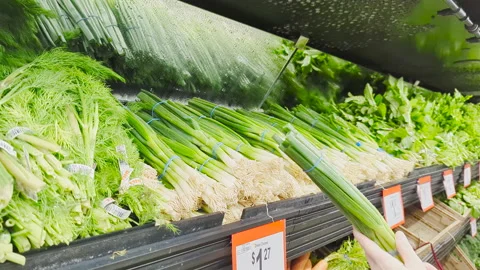 The motion of a woman's hand picking green onion inside a Walmart Stock Footage 239634854