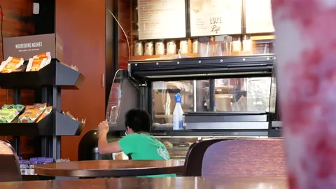 Motion of worker cleaning display rack inside Starbucks store with 4k resolution Video stock 93626173