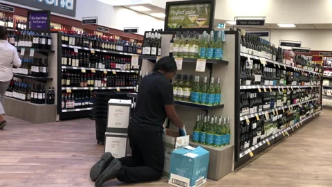 Motion of worker exhibiting wine on the display rack inside BC liquor store Stock Footage 114875417