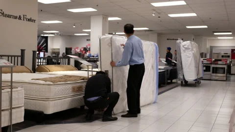 Motion of worker moving new mattress for sale inside The Bay store Stock Footage 89260888