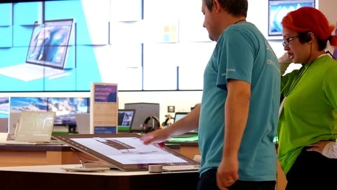 Motion of worker showing new display computer at Microsoft store Stock Footage