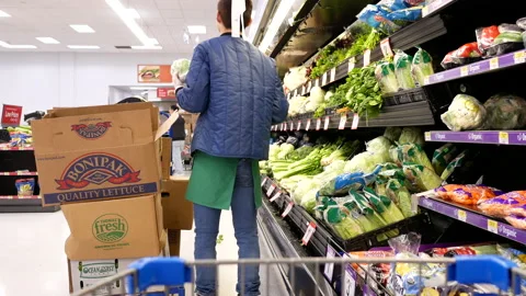 Motion of worker stocking lettuces on display rack inside Walmart store Stock Footage 85549356