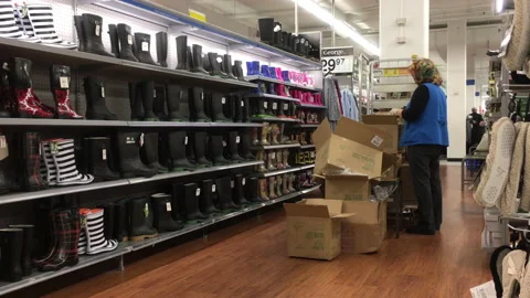 Motion of worker stocking shoes on display rack inside Walmart store Stock Footage 121788920