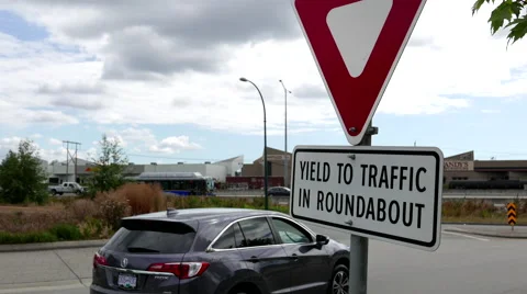 Motion of yield to traffic in roundabout sign with traffic flow background Video stock 66782976