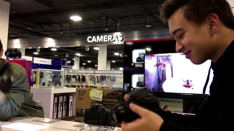 Motion of young man trying new digital camera inside store Video stock 71154342