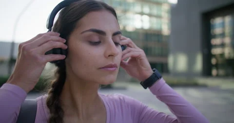 Motivated active female runner concentrated on healthy workout puts on wireless Stock Footage 160203726