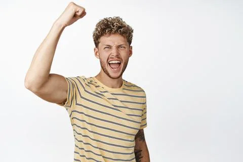 Motivated blond handsome guy rooting, protesting, raising clenched fist and Stock Photos