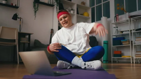 Motivated overweight man doing stretching exercises while watching a tutorial Stock Footage 249211446
