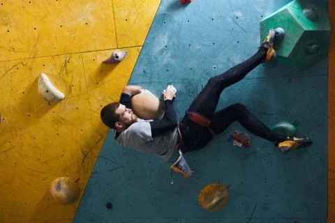 Motivated physically challenged boulderer with beard hanging at climbing wall Stock Photos