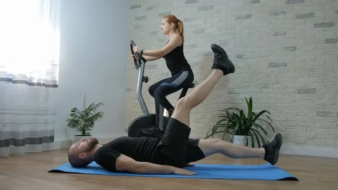 Motivated young couple. Man doing abdominal exercises Stock Footage 128046089