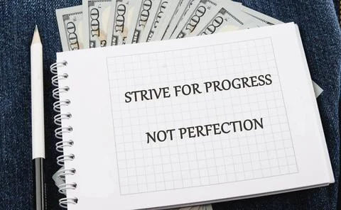 A motivational note reads strive for progress not perfection, resting on deni Stock-Fotos