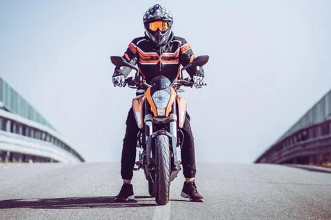 Motor biker ready to go on an empty road. Outdoors adventures and freedom con Stock Photos