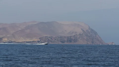 Motor boat sailing with mountain in background near Paracas Peru Stock-Footage 129000474