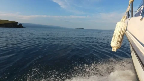 Motor boat sailing. Smooth surface of lake Baikal. Water splashes from boat. Vídeos de archivo 128409914