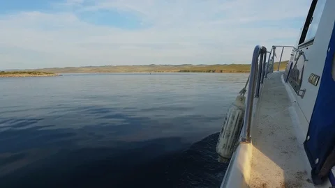Motor boat sailing. Smooth surface of lake Baikal. Water splashes from boat. Video stock 128410205