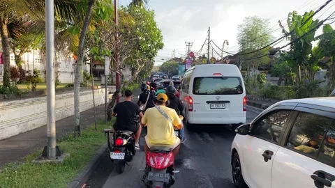 Motorbikes and car drivers navigate in congested traffic in Bali, Indonesia 4K Stock Footage 286396949