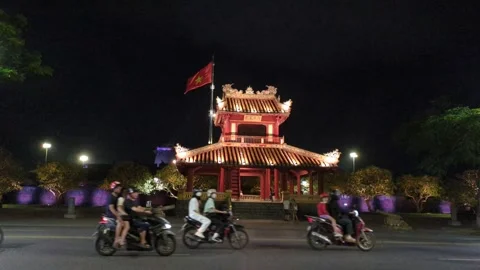 Motorbikes passing by illuminated Phu Van Lau Pavilion of Vietnam at night Stock Footage 313486282