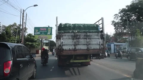 Motorbikes running between big trucks on Semarang inner city road.  Java Video stock 219001591