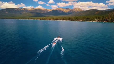 Motorboat leaving a wake beneath mountains at Lake Tahoe. A boat crosses blue Stock Footage 346724909