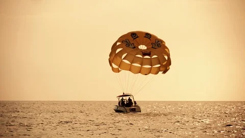 Motorboat is pulling a parachute in the open sea at dark sunset in slow motion Vidéo 111400647