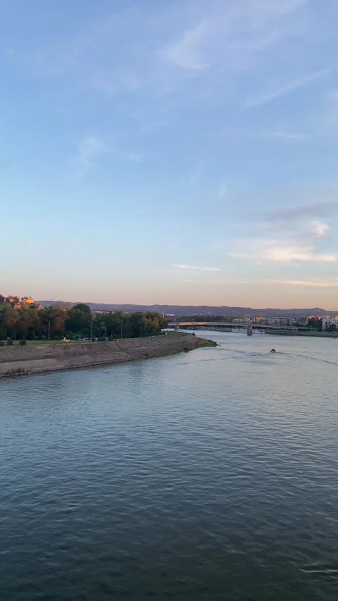 Motorboat on river in urban setting under twilight sky with distant city Stock Footage 339480057