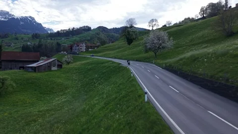 Motorcycle approaching camera on mountain road drone pullback Видео 333011888