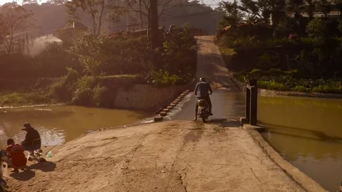 Motorcycle Crossing through River Water via Concrete Ford in Da Lat Stock Footage 85579795