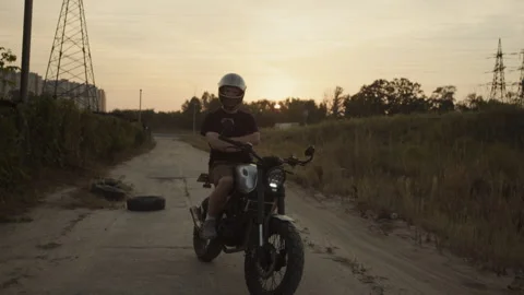 The motorcycle driver stands in the middle of the road strictly looking forward  Video stock 253448075