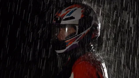 Motorcycle driver wearing helmet and standing in the rain. Stock Footage 80252586