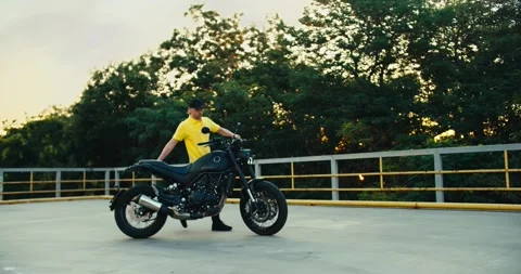 A motorcycle driving instructor in a yellow t-shirt drives motorcycles and sets Stock Footage 249606596
