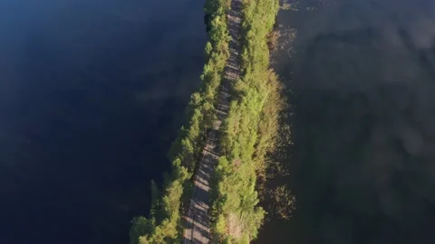 Motorcycle driving on a ridge road between calm lakes in Punkaharju, Finland Stock Footage 158600599