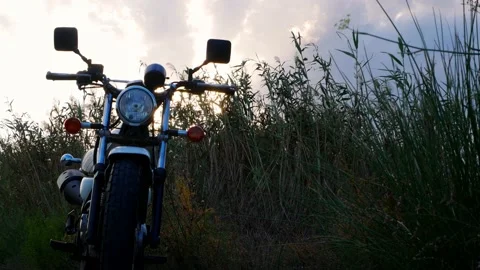 Motorcycle in the forefront, late evening sun flashing through tall herbs. Video stock 139541212