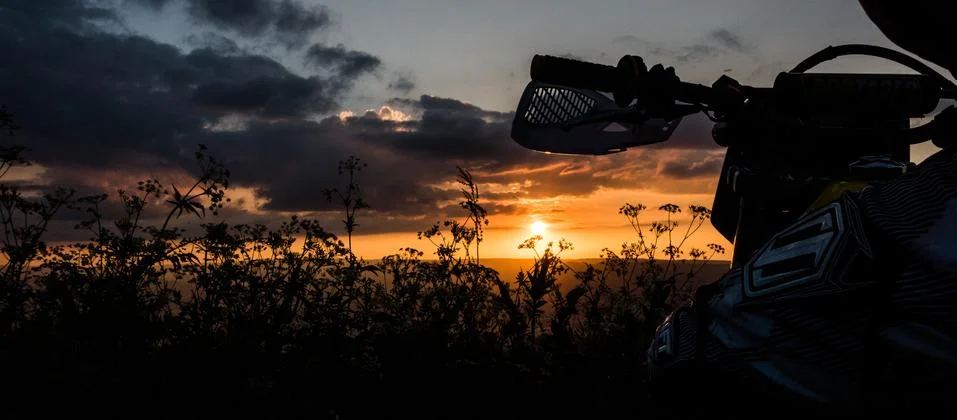 Motorcycle in the grass at sunset Stock Photos