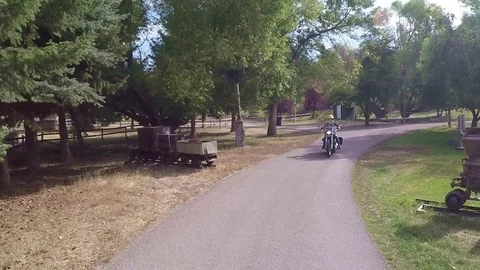 Motorcycle leaving a ranch riding zig-zag road between trees - pov 動画素材 83399249